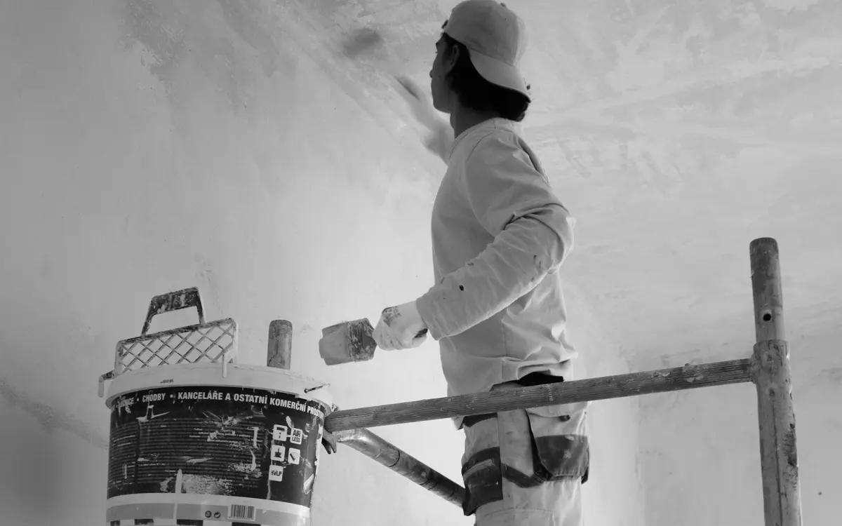 Pintor trabalhando em parede sobre andaime